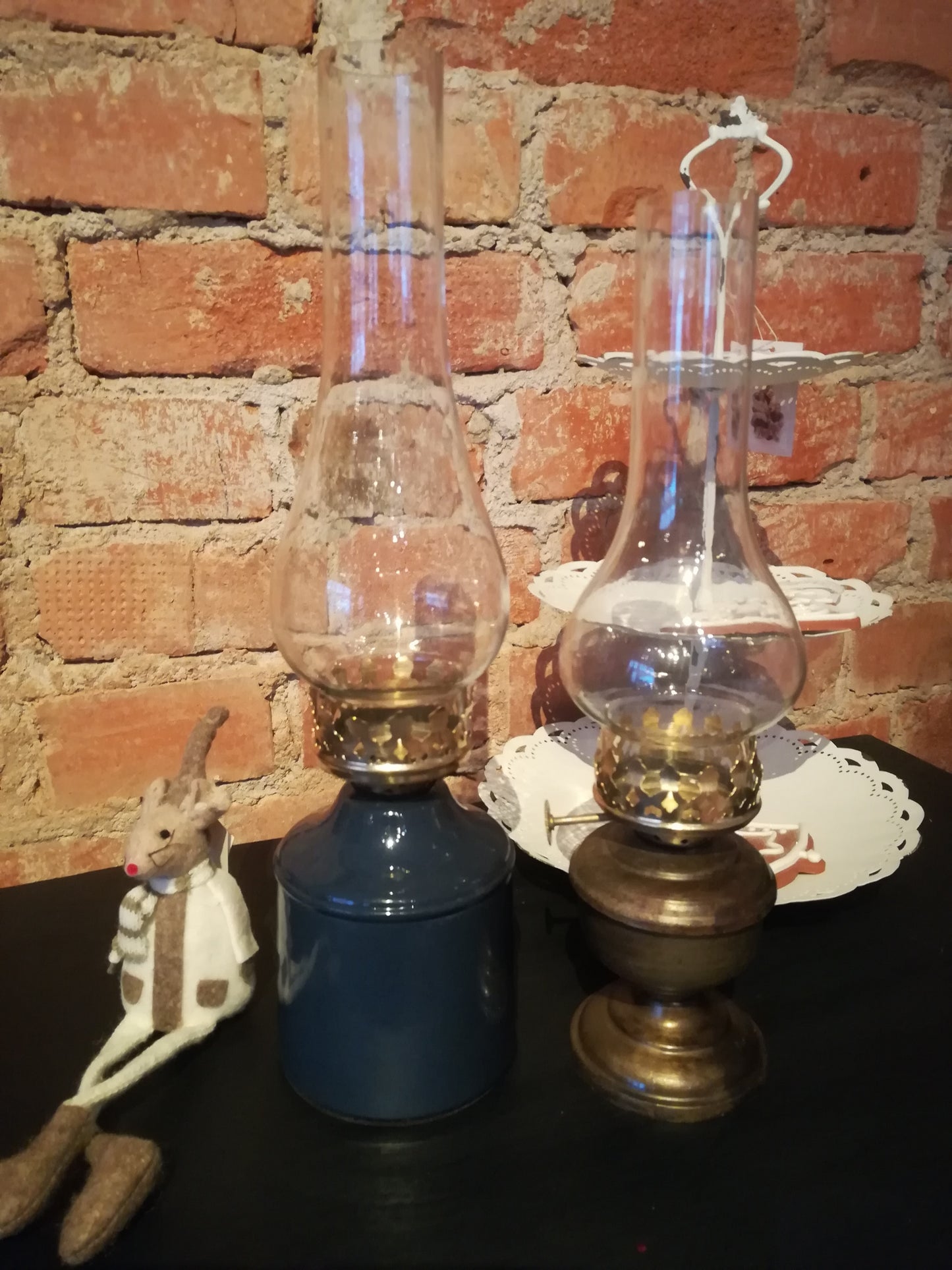 Lampa för värmeljus: Värmeljuslykta med utseendet av en gammal fotogenlampa med fot i antikmässing och glaskupa som skyddar lågan. Till Värmeljus. Ingår ej. Mått: H 27cm B 10cm Material: Emalj, Metall & Glas