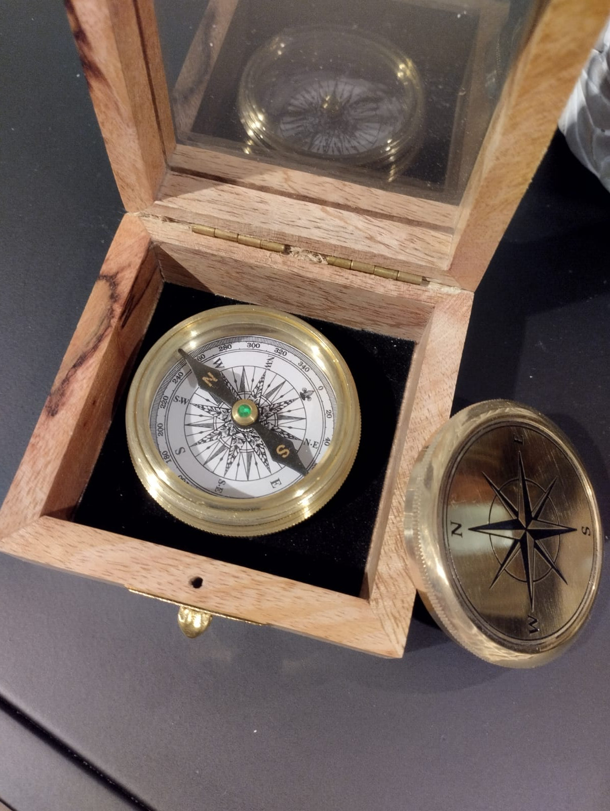 Kompass i elegant trälåda.  Mått Trälåda: 9x9cm, H4,5cm  Mått: Kompass: Diameter 6cm, H 2cm  Material: Trä, Metall, Glas