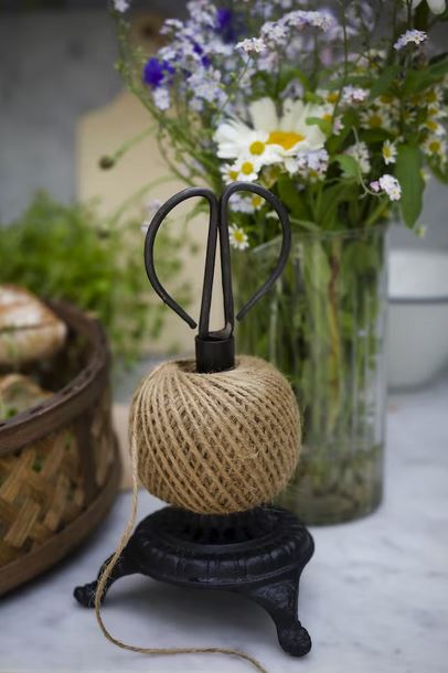 En dekorativ snörhållare i gjutjärn inklusive jutesnöre och en liten sax. Vacker inredningsdetalj som också blir en perfekt hjälpreda i trädgården eller vid bordet för paketinslagning.  Material: gjutjärn