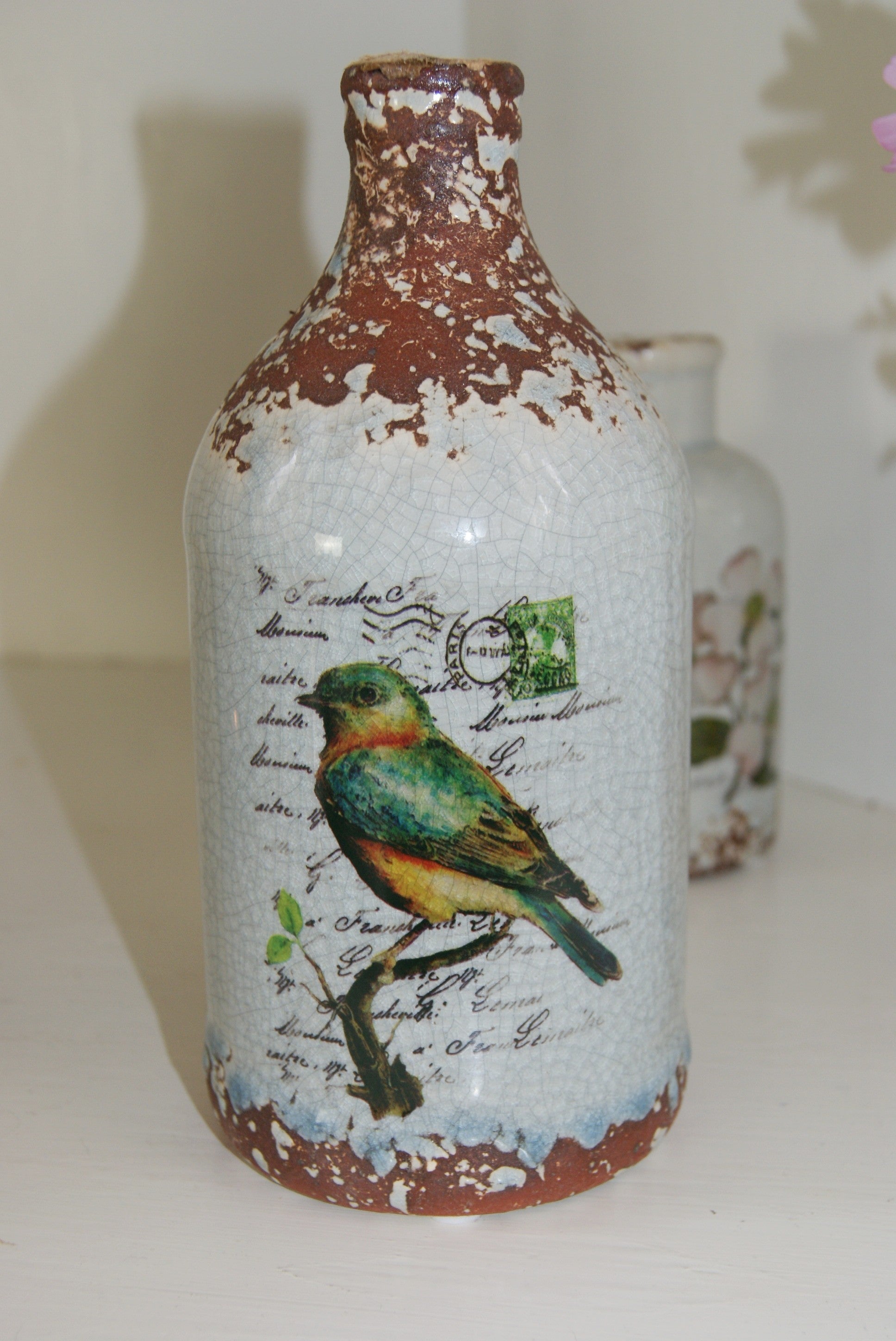 Vas/flaska i keramik med fågelmotiv. Vacker blickfångare med "used" optik.  Mått: Ø 10, H 20 cm Material: Keramik